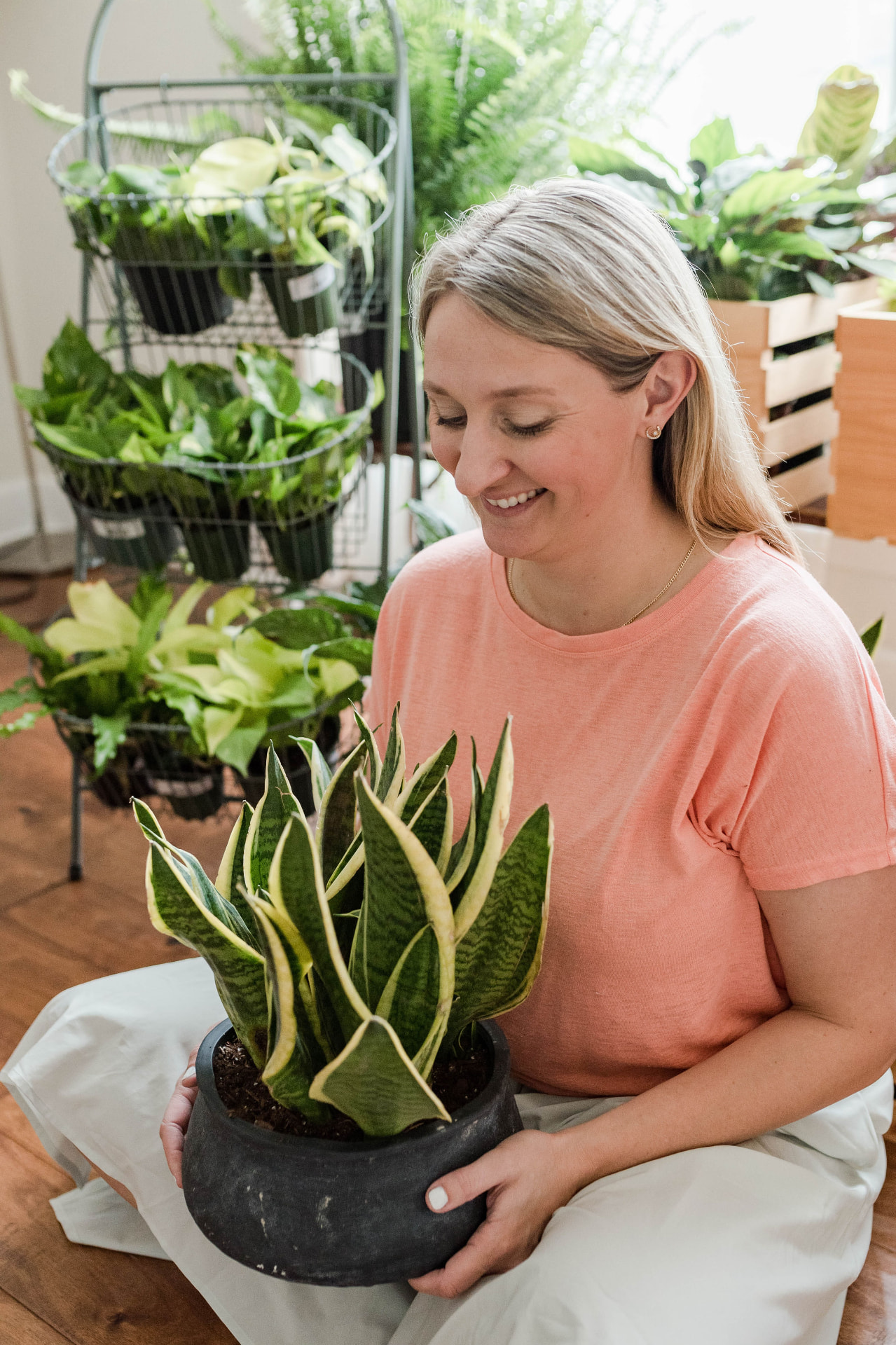 Katie Iarca smiling while holding a potted snake plant in a plant shop